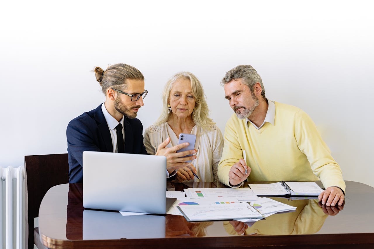 gallery-04 Three individuals collaborating on financial documents during a business meeting.